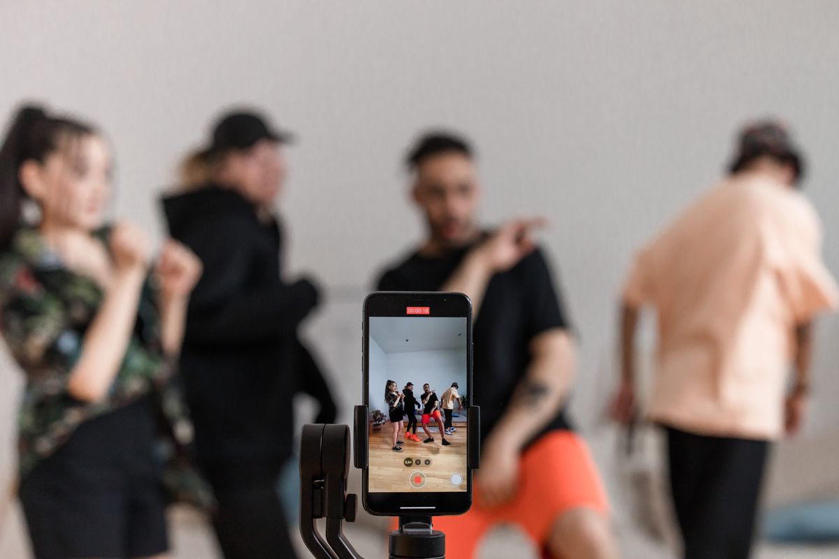 Команда друзів планує контент для TikTok за столом з ноутбуком і смартфоном на штативі
